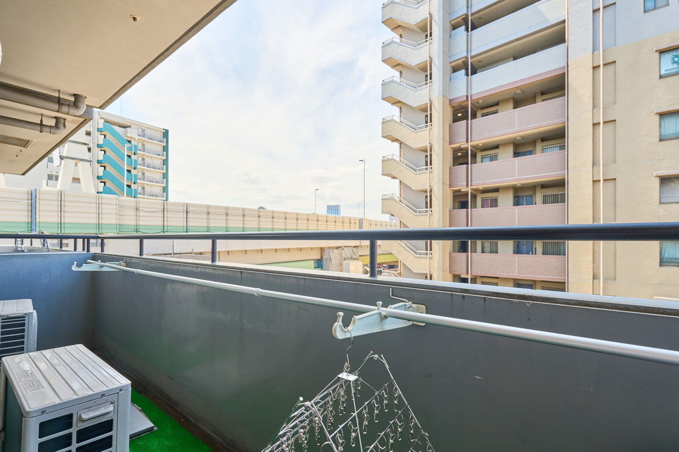 Ein Balkon mit Metallgeländer, einem kleinen Tisch und einer Wäscheständer.