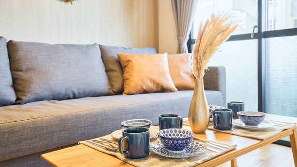 A cozy living room with a grey sofa, a wooden coffee table, and a vase with dried plants.