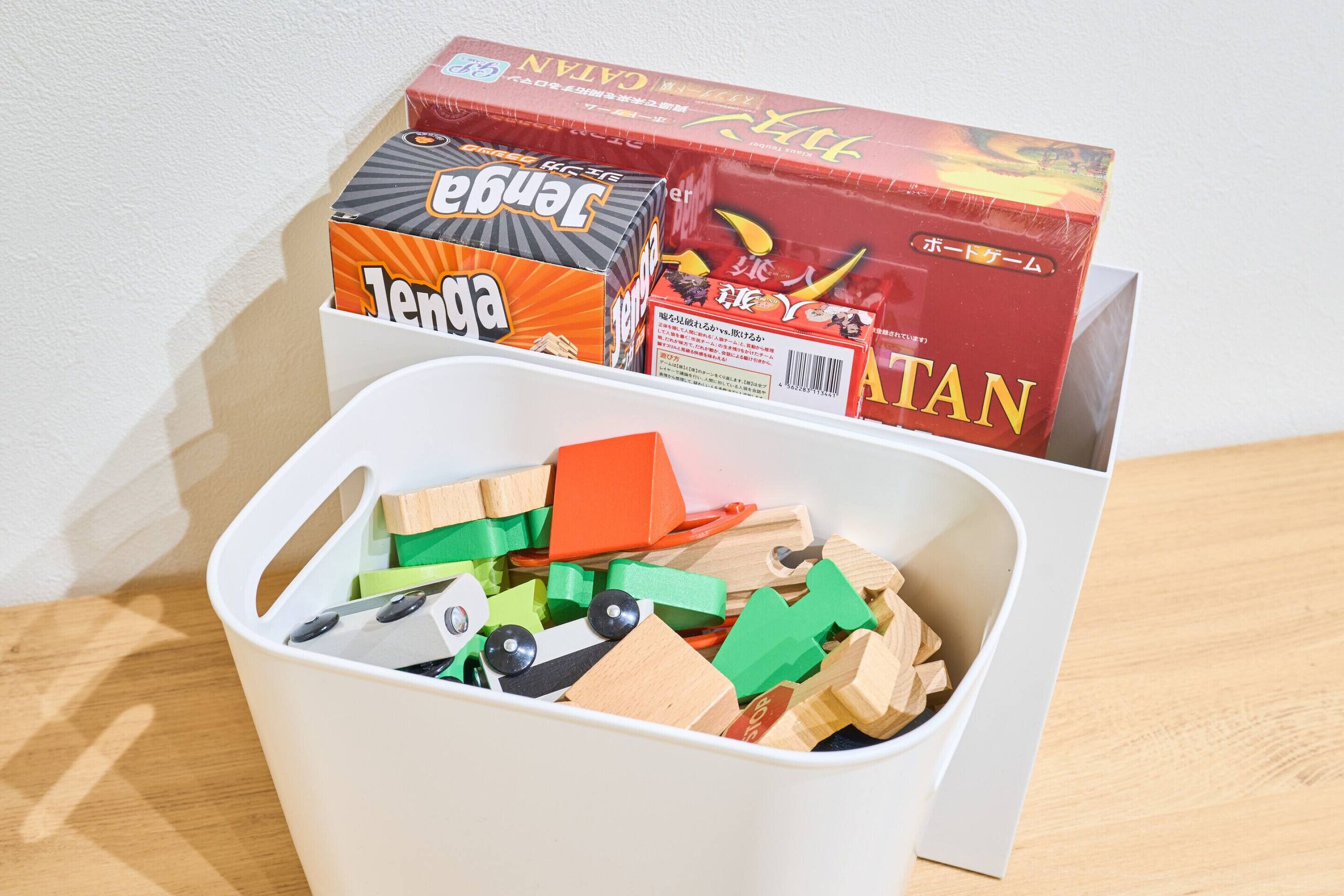 A storage bin filled with wooden blocks and two boxes of building blocks.