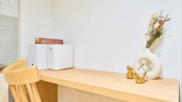 Ein Holztisch mit einer weißen Vase voller getrockneter Blumen, einer kleinen goldenen Figur und einem Buch mit dem Titel 'Catan'.