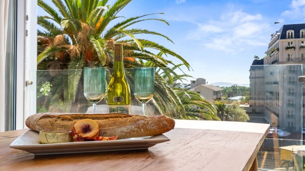 A table with a baguette, cheese, and fruit, and two wine bottles behind a glass partition. - Greenpark 202 (Cape Town)