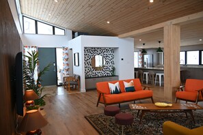 Un salon moderne avec un canapé, des fauteuils, une table basse et un coin cuisine à l’arrière-plan.