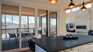 A modern kitchen with a large island, sliding glass doors leading to a deck, and a fireplace.