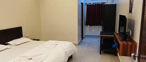 A hotel room with a bed, a ceiling fan, a TV, and a desk.