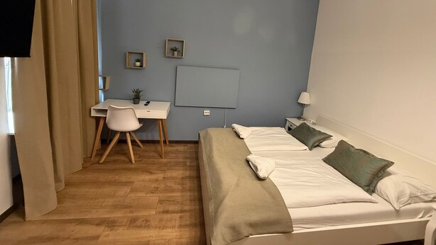 A bedroom with a bed, a desk, a chair, and a TV. - Stylish 1BR Apartment Near Westbahnhof (Vienna)
