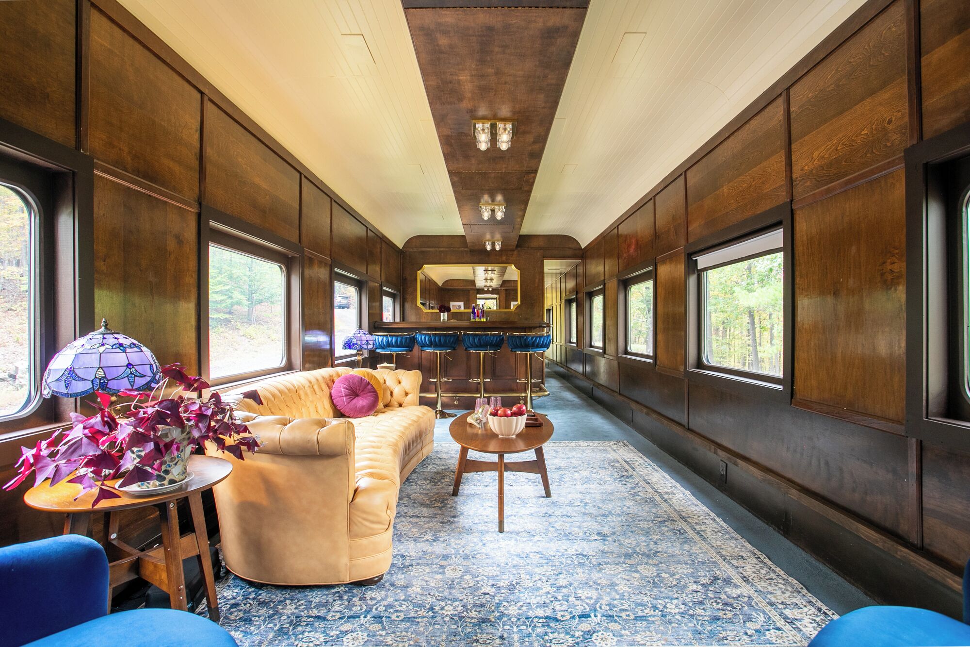 L'intérieur d'un wagon de train, avec un canapé, un bar et de grandes fenêtres.