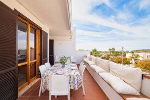 A balcony with a dining table, chairs, and a sofa.