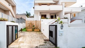 Un immeuble résidentiel moderne doté d’une cour fermée par un portail, d’un balcon et d’un escalier.