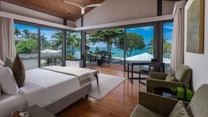 A modern bedroom with a large bed, a seating area, and a view of the ocean. - Villa Cielo (Takua Thung)