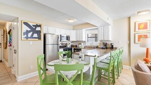 A modern kitchen with white cabinets, a central island, and green chairs. - Seaside Beach & Racquet 4912 (Orange Beach)