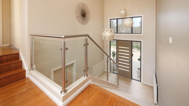 A modern interior with a glass railing staircase, a decorative wall piece, and a globe pendant light. - Peregrine Pool Paradise - Outstanding four bedroom family home with pool! (Wodonga)