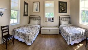 A room with two single beds, a chest of drawers, and a window. - Colorful Waterfront Cabin Rentals on the Braden River near Sarasota, Florida (Bradenton)