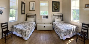 Ein Zimmer mit zwei Einzelbetten, einer Kommode und einem Fenster.