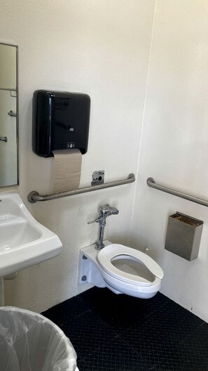 Een toiletruimte met toilet, handdroger en handdesinfecteerder.