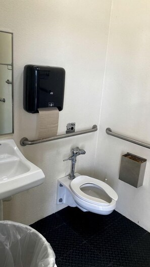 Eine Toilette mit Handtrockner und Handdesinfektionsmittelspender.