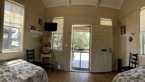 A room with two beds, a television, a door leading outside, and a small table with a lamp. - Colorful Waterfront Cabin Rentals on the Braden River near Sarasota, Florida (Bradenton)