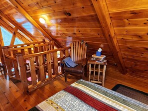 Un interior de madera con una silla de madera, una mesita pequeña y un tapete estampado.