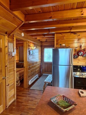 Ein Holzblockhaus mit Küche, Essbereich und Schlafzimmer.