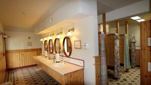 Une salle de bain avec un lambris en bois, un long meuble-lavabo doté de trois miroirs et un sol à motifs.