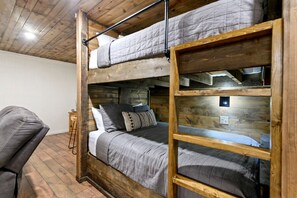 A bunk bed with a wooden frame, a bedside table, and a chair. - Wonderful Cabin Perfect for Family Getaways in Broken Bow, Oklahoma (Broken Bow)