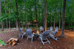 A group of Adirondack chairs arranged around a campfire in a forested area. - Wonderful Cabin Perfect for Family Getaways in Broken Bow, Oklahoma (Broken Bow)