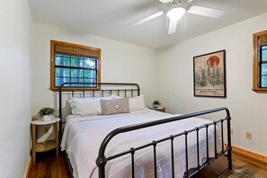 A bedroom with a bed, a window, a ceiling fan, and a framed picture on the wall. - Wonderful Cabin Perfect for Family Getaways in Broken Bow, Oklahoma (Broken Bow)