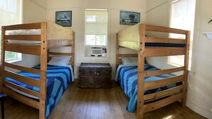 A room with two bunk beds, a chest of drawers, a chair, and a window.