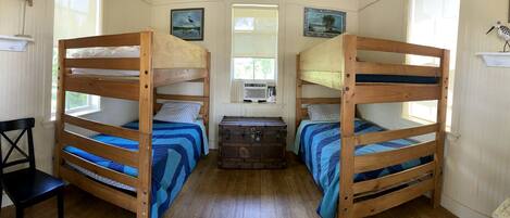 A room with two bunk beds, a chest of drawers, a chair, and a window.