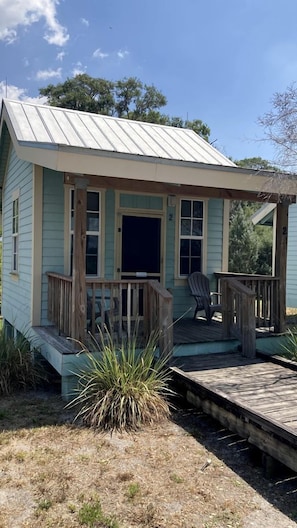A small, single-story house with a porch, two windows, and a door.