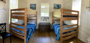 Ein Zimmer mit zwei Etagenbetten, einer Kommode, einem Stuhl und einem Fenster.