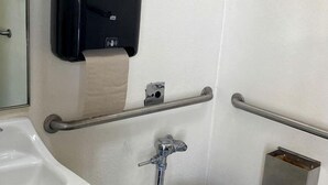 A restroom with a toilet, hand dryer, and hand sanitizer dispenser.