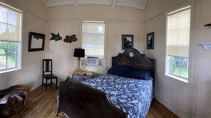 A bedroom with a bed, a chair, a nightstand, a lamp, and wall decorations. - Lakefront Cabin Rental in Bradenton, Florida (Bradenton)