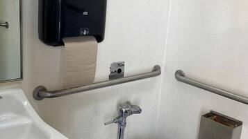 A restroom with a toilet, hand dryer, and hand sanitizer dispenser.