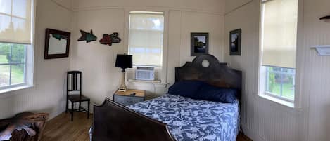 A bedroom with a bed, a chair, a nightstand, a lamp, and wall decorations.