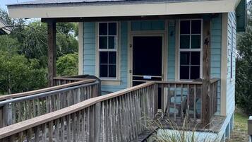 Une petite construction en bois, surmontée d’un toit en métal, avec une terrasse en bois menant à l’intérieur et une porte.
