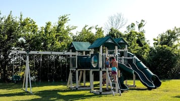 Une aire de jeux avec un toboggan et des balançoires.