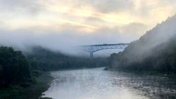 Une rivière avec un pont au loin, entourée d’une végétation luxuriante.