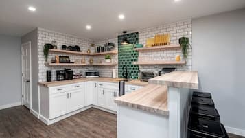 Eine moderne Küche mit weißen Schränken, Holz Arbeitsplatten und einer grünen Rückwand.