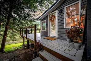 A house with a wooden deck, a front door with a wreath, and a 'Hello' sign.