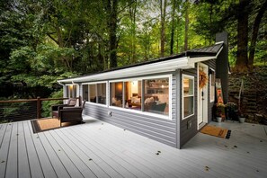 A modern cabin with large windows, a deck, and a welcoming sign. - Scenic Retreat: Riverfront Cabin with Large Deck and Fire Pit in Emlenton, Pennsylvania (Emlenton)