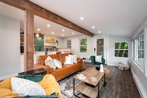 Un salon moderne avec un canapé en cuir marron, un fauteuil vert et une table basse en bois.