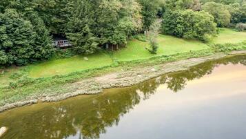 A river with a house surrounded by dense trees.
