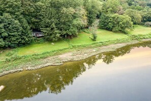 A river with a house surrounded by dense trees.