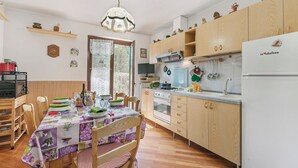 A kitchen with wooden cabinets, a dining table with chairs, and a chandelier. - Maison Rosamunda for 6 With Garden (Oulx)