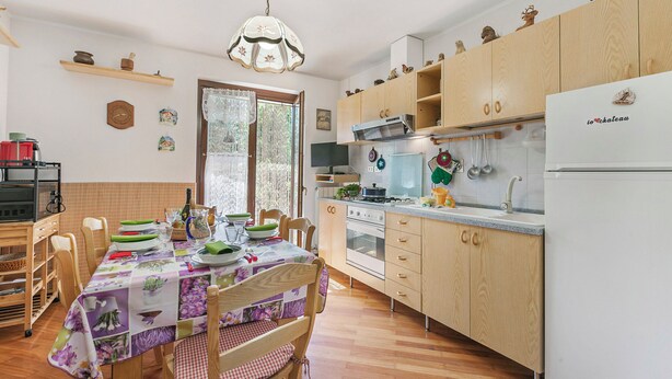 A kitchen with wooden cabinets, a dining table with chairs, and a chandelier. - Maison Rosamunda for 6 With Garden (Oulx)