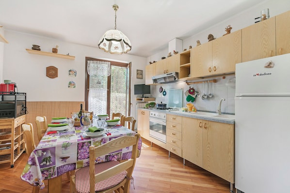 A kitchen with wooden cabinets, a dining table with chairs, and a chandelier.