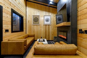 A wooden interior with a fireplace, framed artwork, and leather seating.