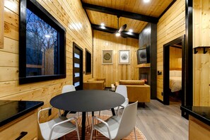 Un interior de madera con una mesa redonda, sillas, un sofá y una chimenea.