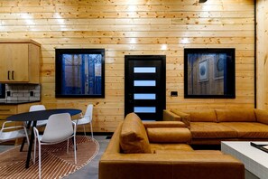 A log cabin interior with a dining area, a sofa, and two framed pictures on the walls.
