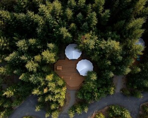 An aerial view of a wooden deck surrounded by dense trees, with two white umbrellas and a bench. - Large and Spacious Double Bell Tents Great for Families in Carson, Washington (Carson)